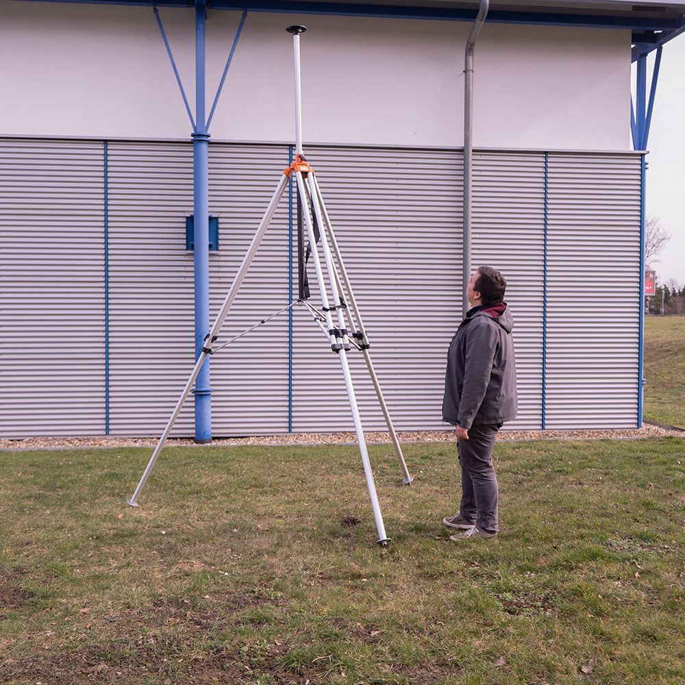 A man is standing next to a tripod in the grass