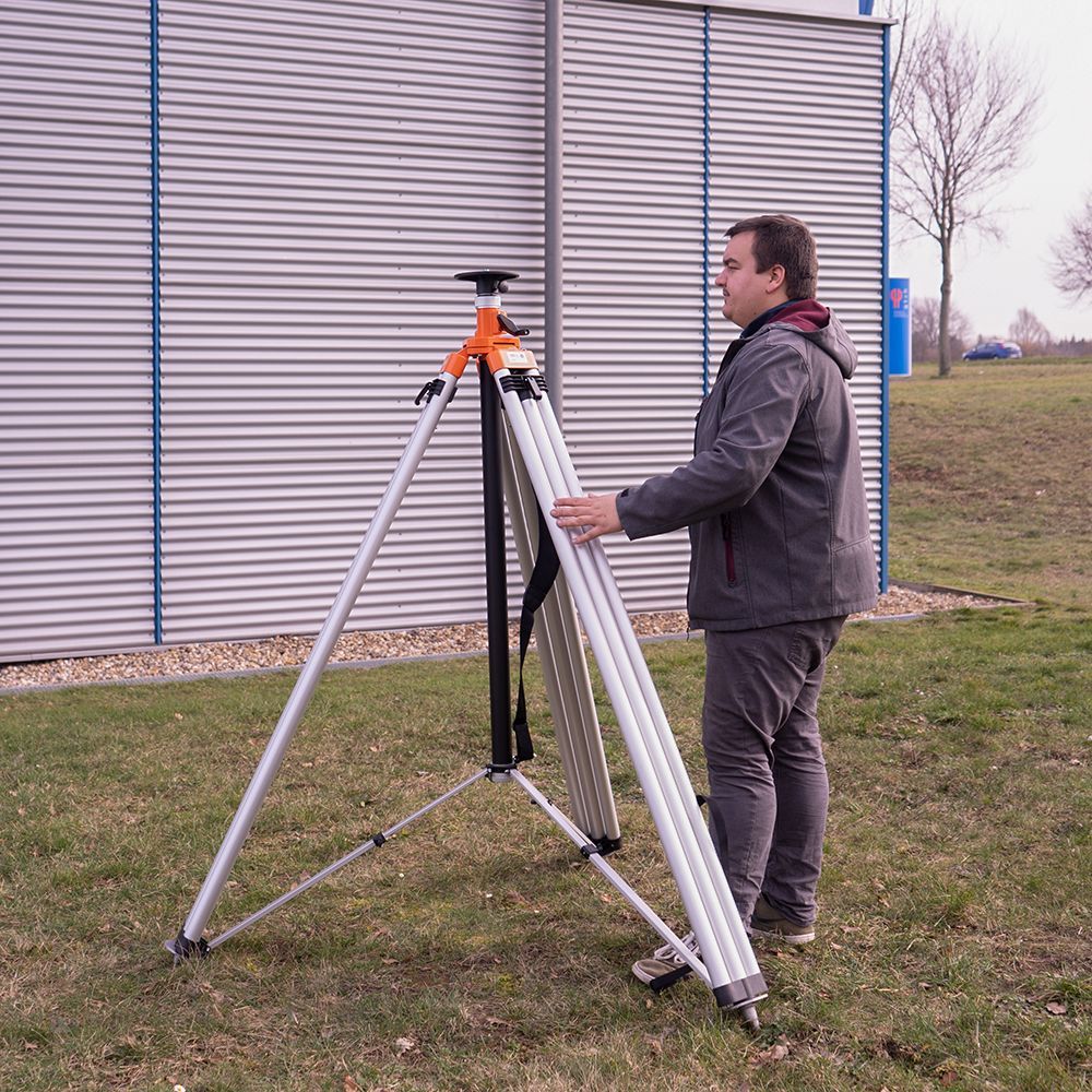 A man is standing next to a tripod in the grass