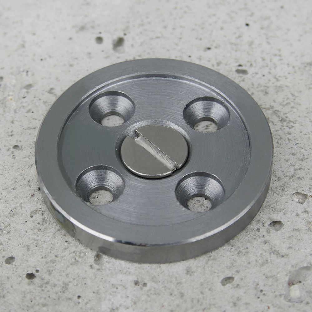 A metal disc with three holes and a screw in the middle