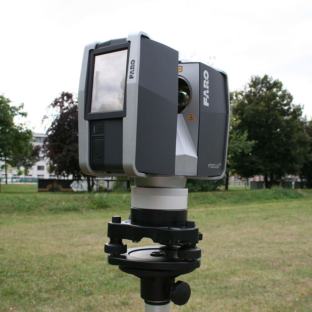 A faro camera is sitting on a tripod in a field