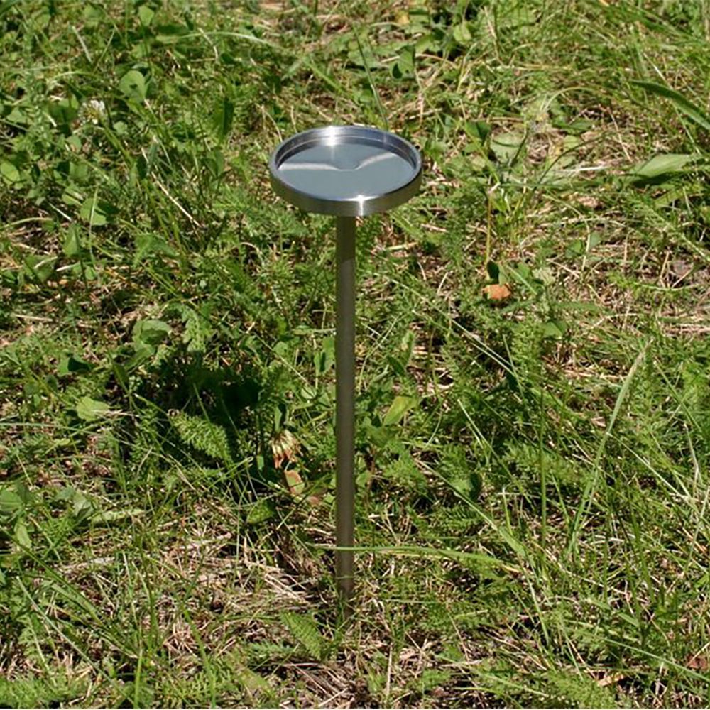 A white ball is sitting on a metal pole in the grass