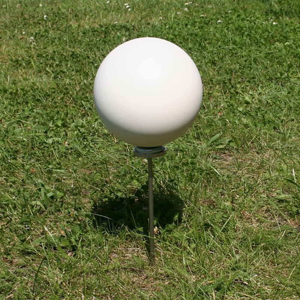 A white ball is sitting on a metal pole in the grass