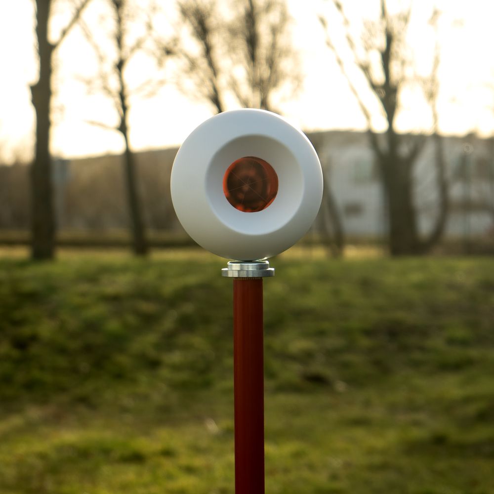 A white object with a red center is on a red pole
