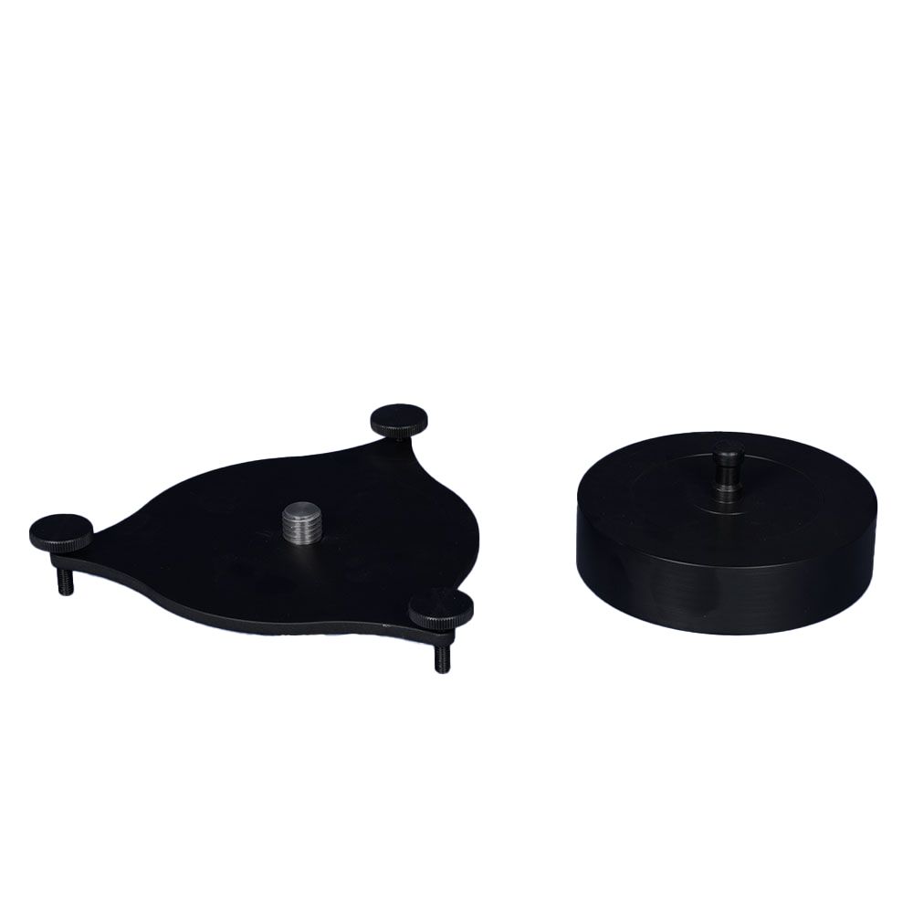A black object with a screw in it is sitting on top of a white surface.