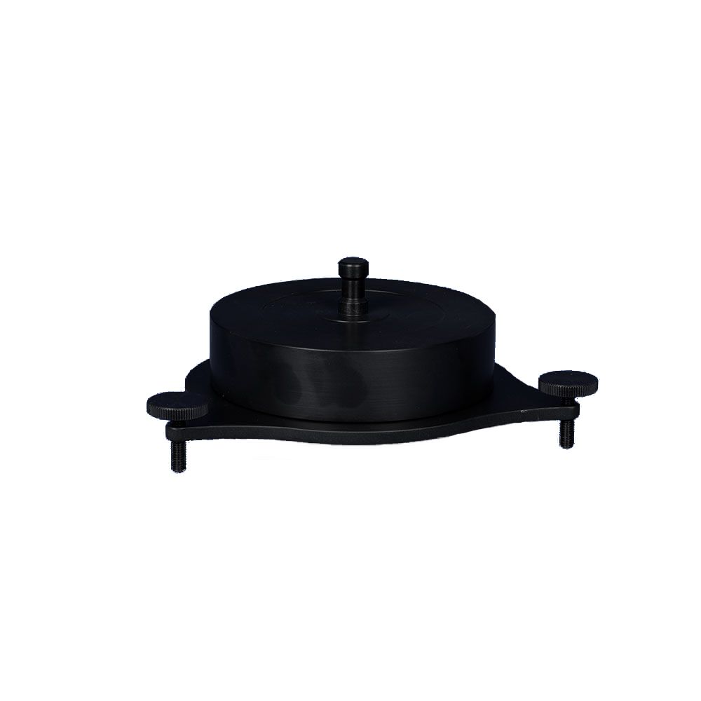 A black object with a screw in it is sitting on top of a white surface.