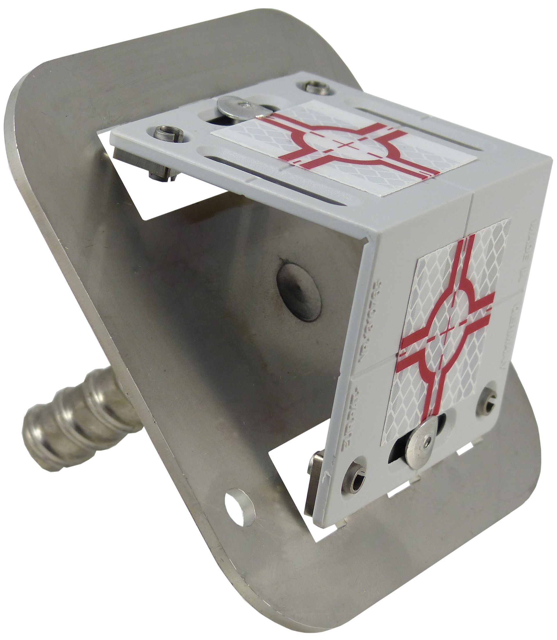 A red cube with a white cross on it sits on a metal plate