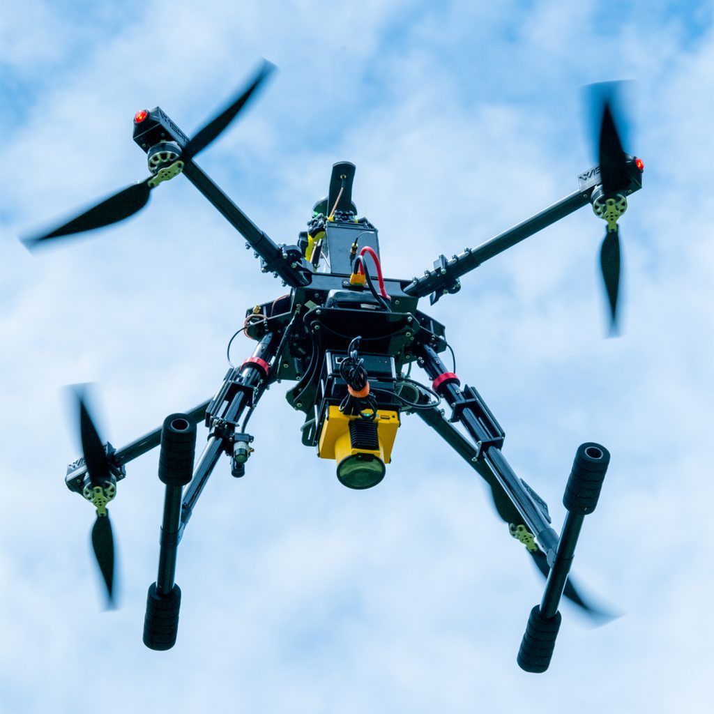 A black and yellow drone is flying in the sky
