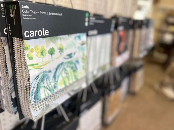 A row of fabric samples hanging on a rack in a store.