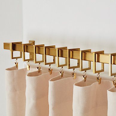 A row of curtains hanging on a wall with brass hooks
