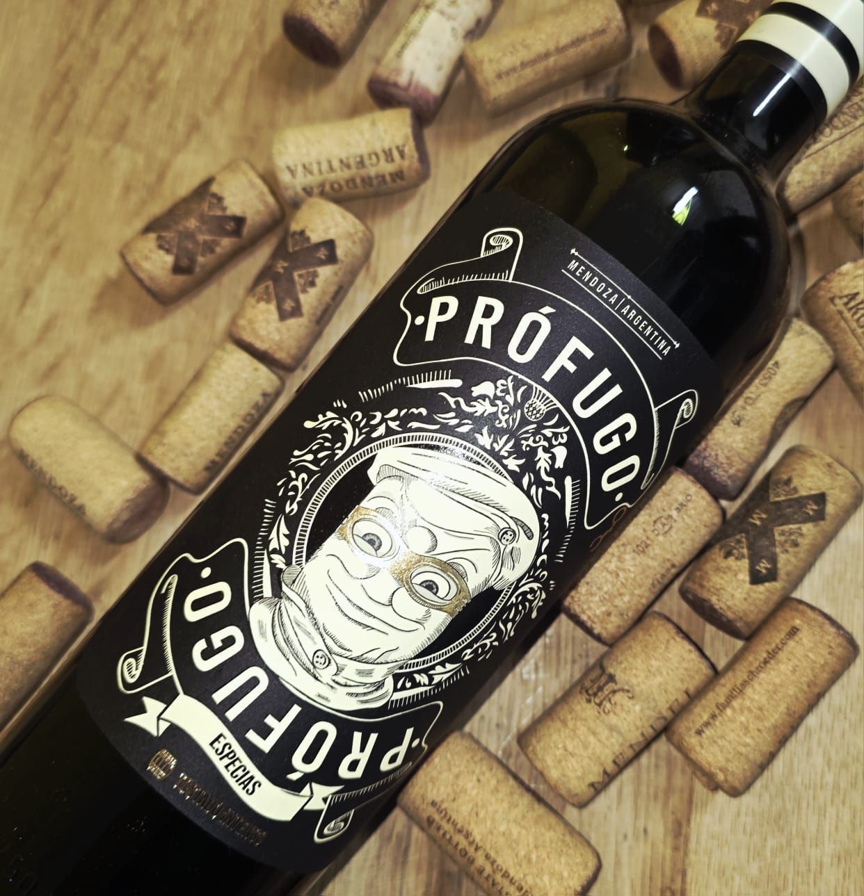 Una botella de vino tinto Prófugo con etiqueta ilustrada, apoyada sobre una superficie de madera