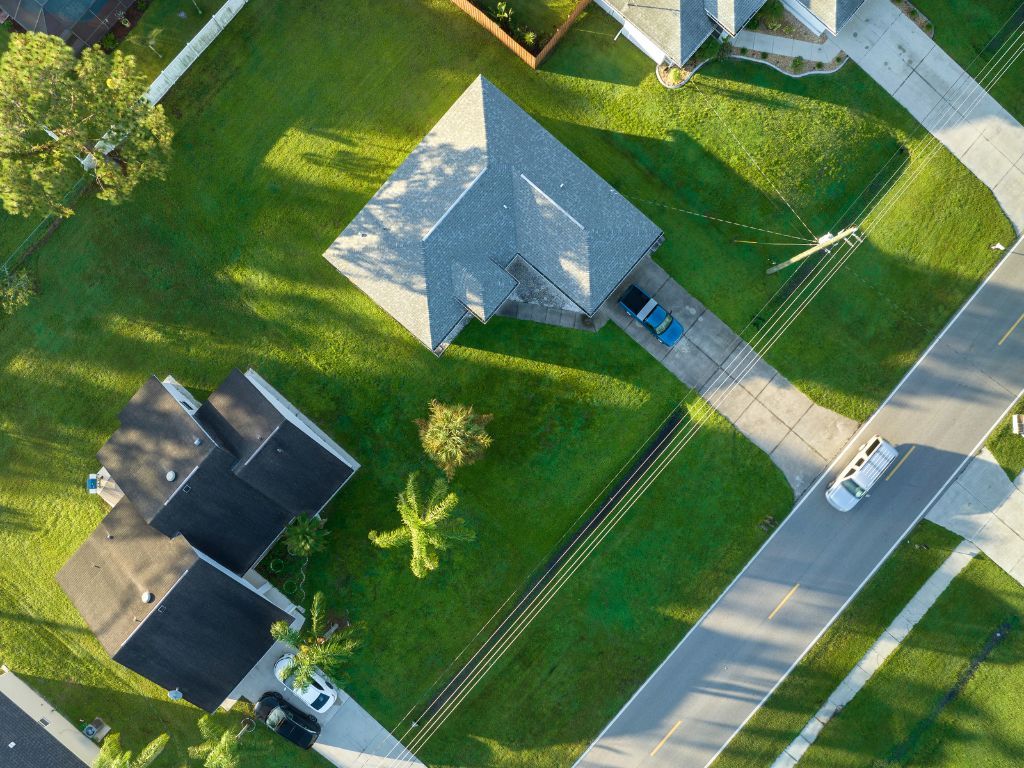 Aerial view of houses with green lawns, driveways, and a street.