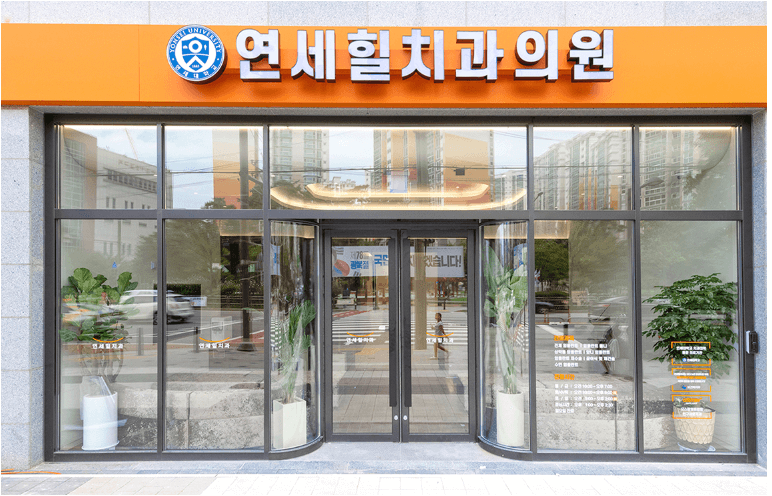 Exterior view of a dental clinic with large glass windows and a bright orange sign.