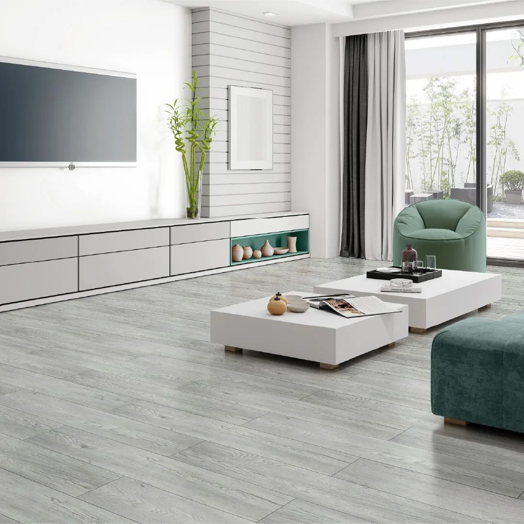 A living room with a television , coffee table , chair , and ottoman.