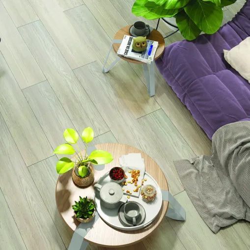 A living room with a purple couch and a wooden table with plants on it.