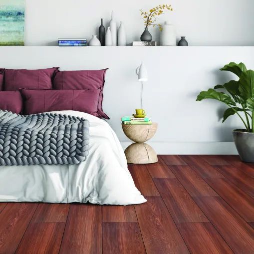A bedroom with hardwood floors and a bed with purple pillows