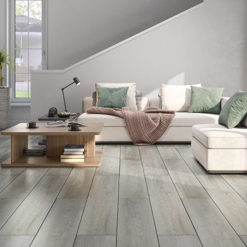 A living room with a couch , ottoman , coffee table and stairs.