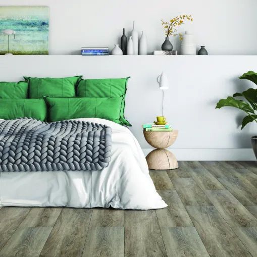 A bedroom with a bed with green pillows and a knitted blanket