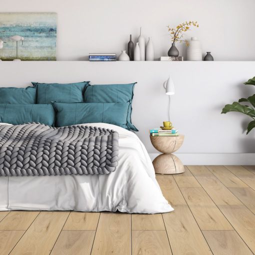A bedroom with a bed , nightstand , lamp and a painting on the wall.