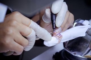 Hands in gloves using a pen to detail a jewelry ring.