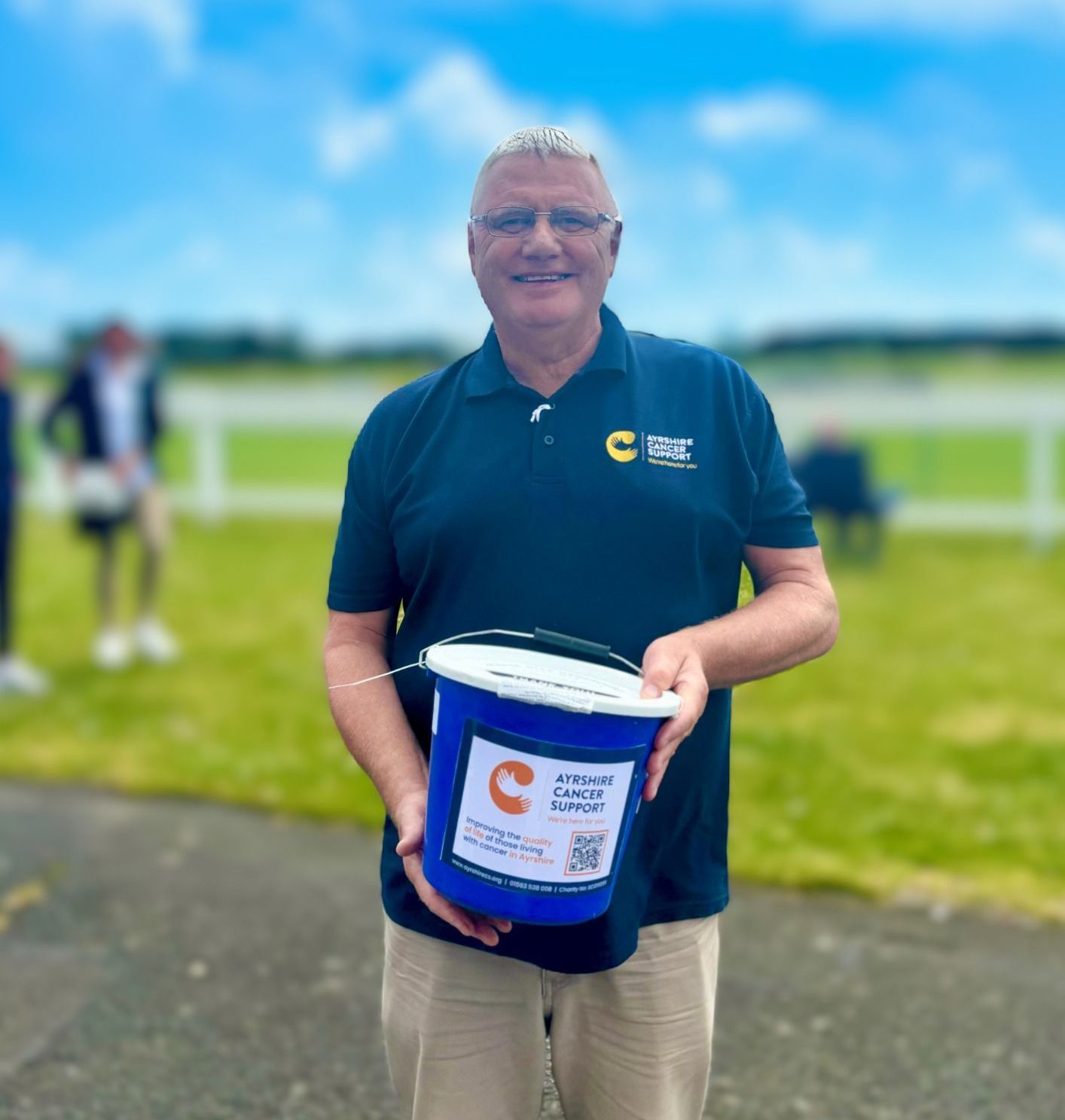 A volunteer holding a blue bucket for donations.