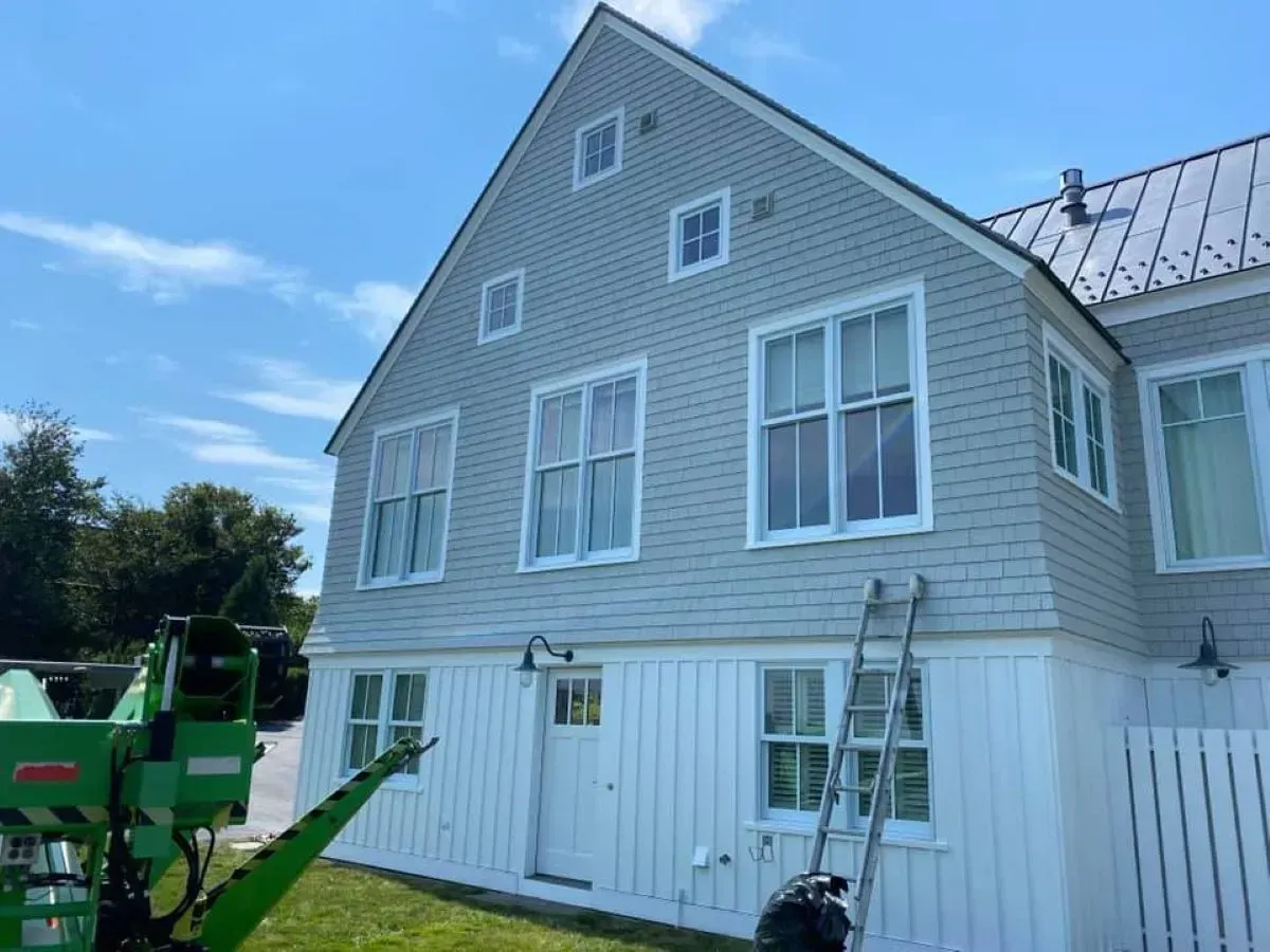 A large white house with a green lift in front of it.