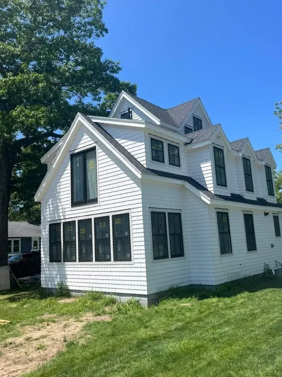 A large white house with a lot of windows is sitting on top of a lush green field.