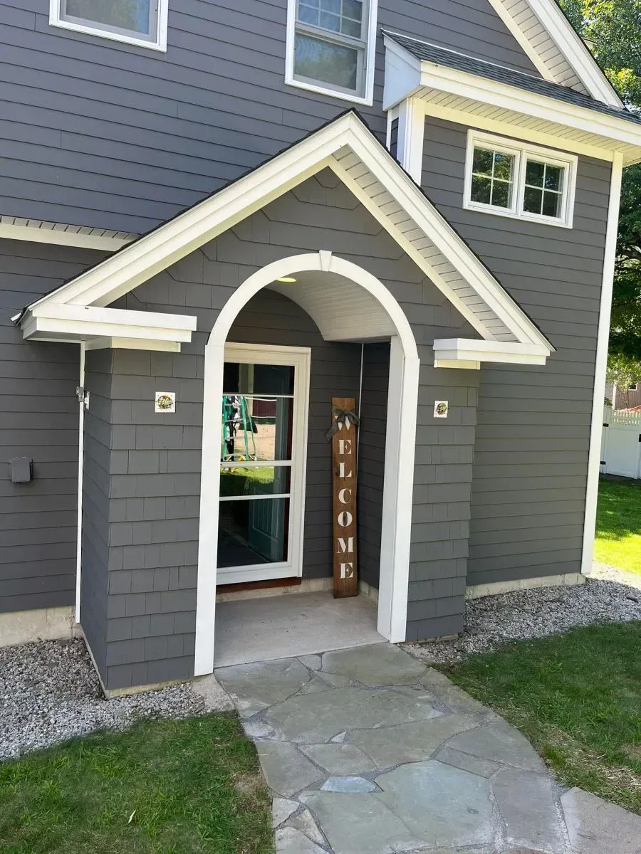 A gray house with a welcome sign in front of it