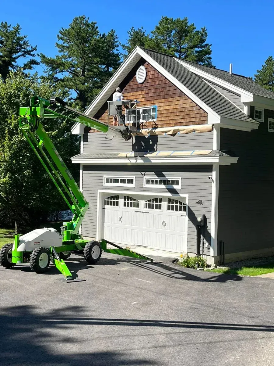 A green crane is working on the side of a house.