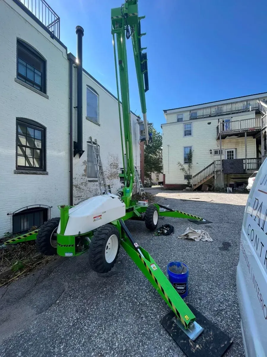 A green and white crane is parked in front of a building.