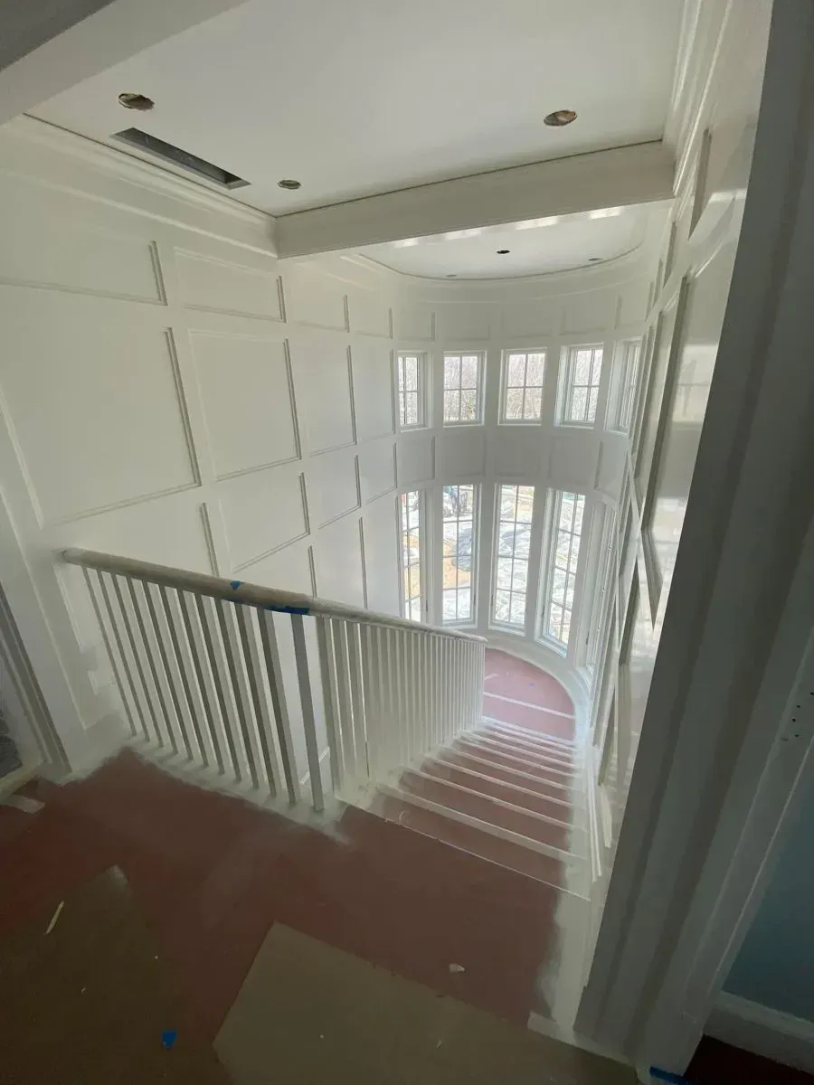 A staircase in a house with a white railing and a red carpet.