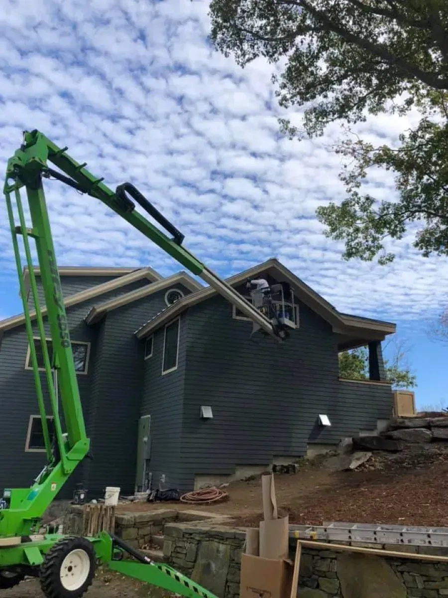 A green crane is sitting in front of a house.