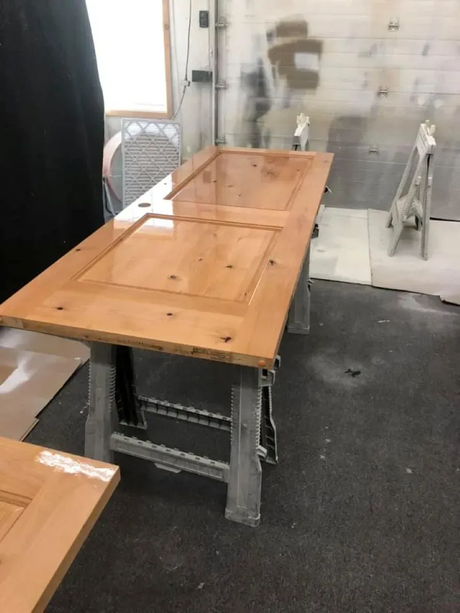 Wooden picnic table and bench in an indoor room with carpeted floor and translucent wall panels