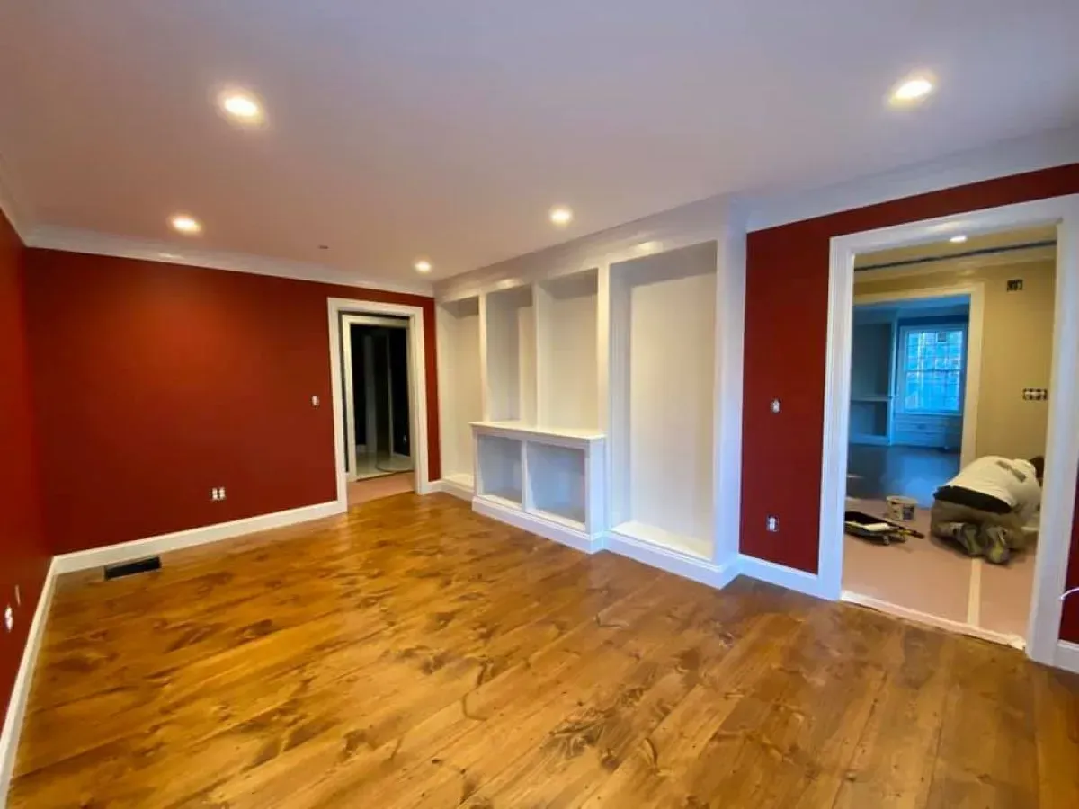 A living room with red walls and hardwood floors.