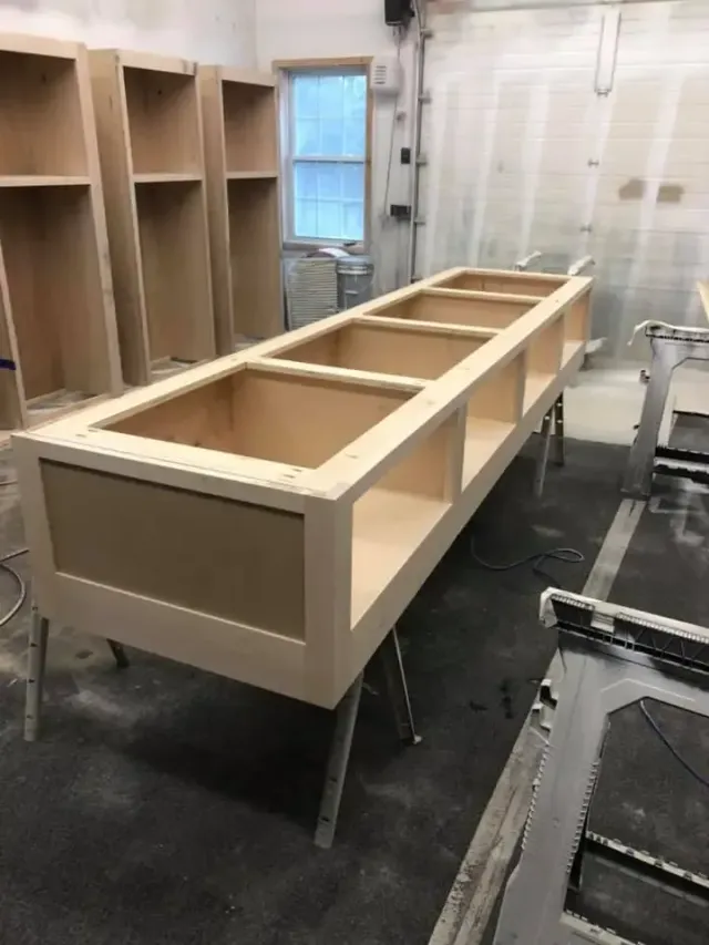 A long wooden cabinet is being built in a workshop.