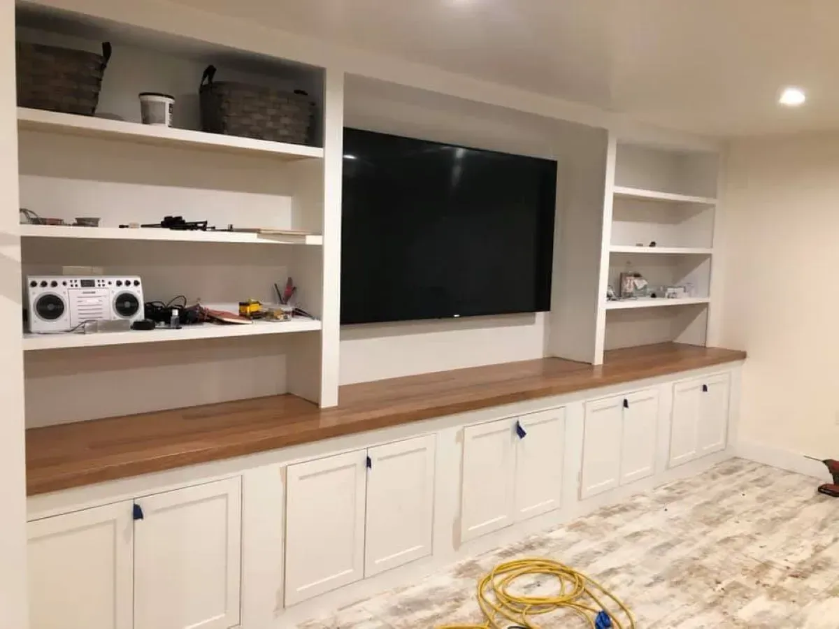 A living room with built in shelves and a flat screen tv.