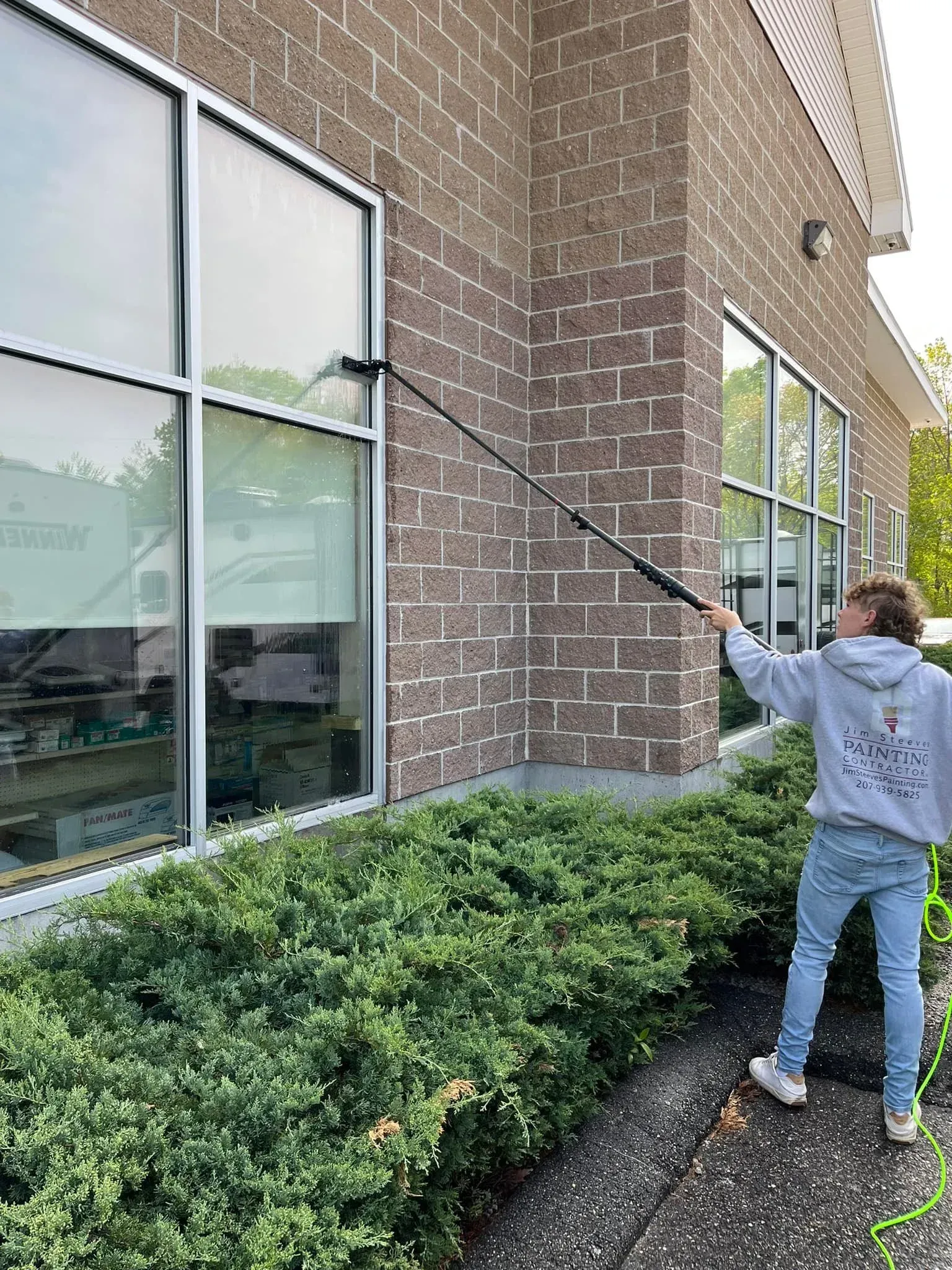 A man is cleaning the windows of a building with a high pressure washer.