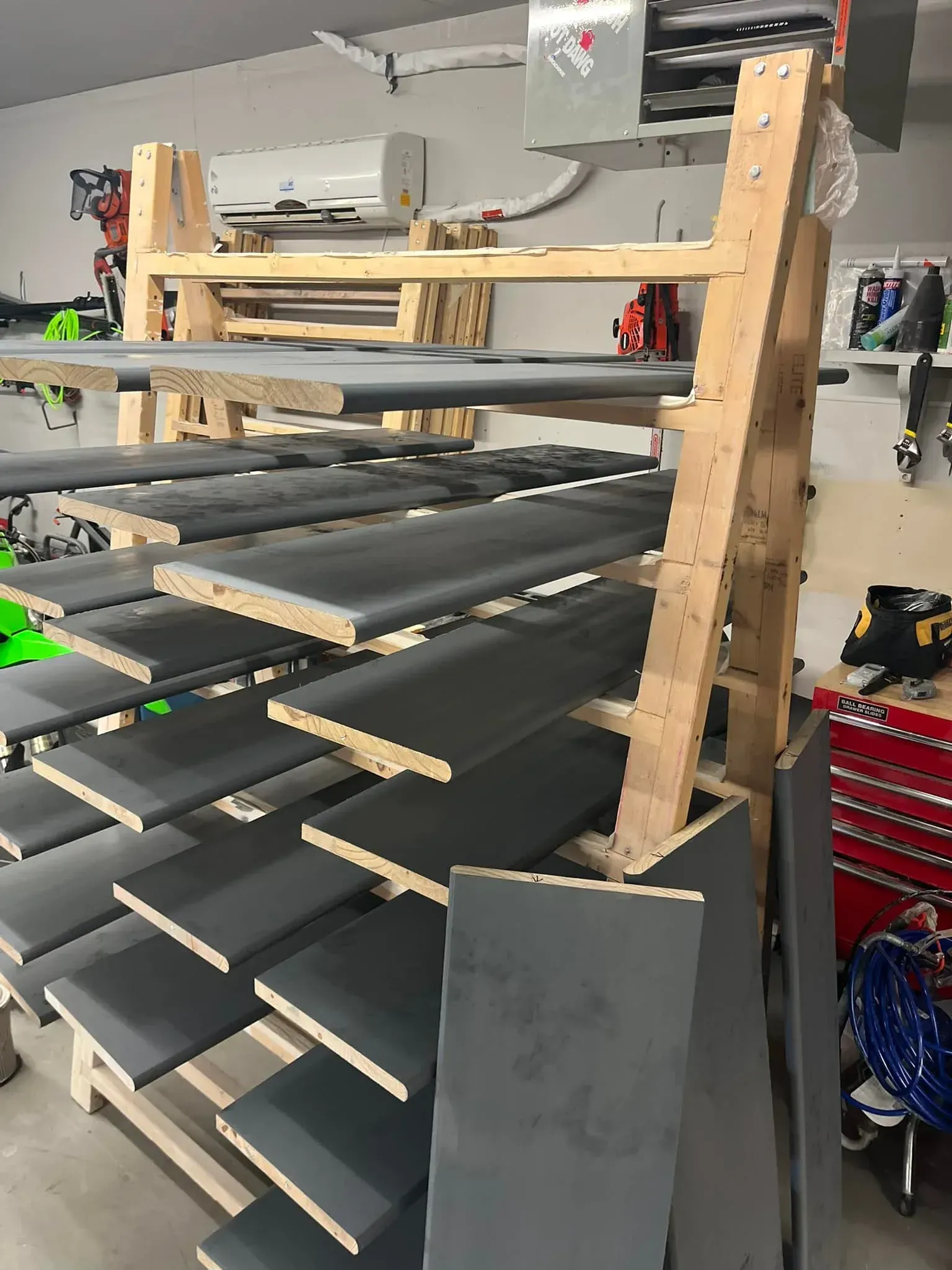 A wooden rack filled with gray boards in a garage.