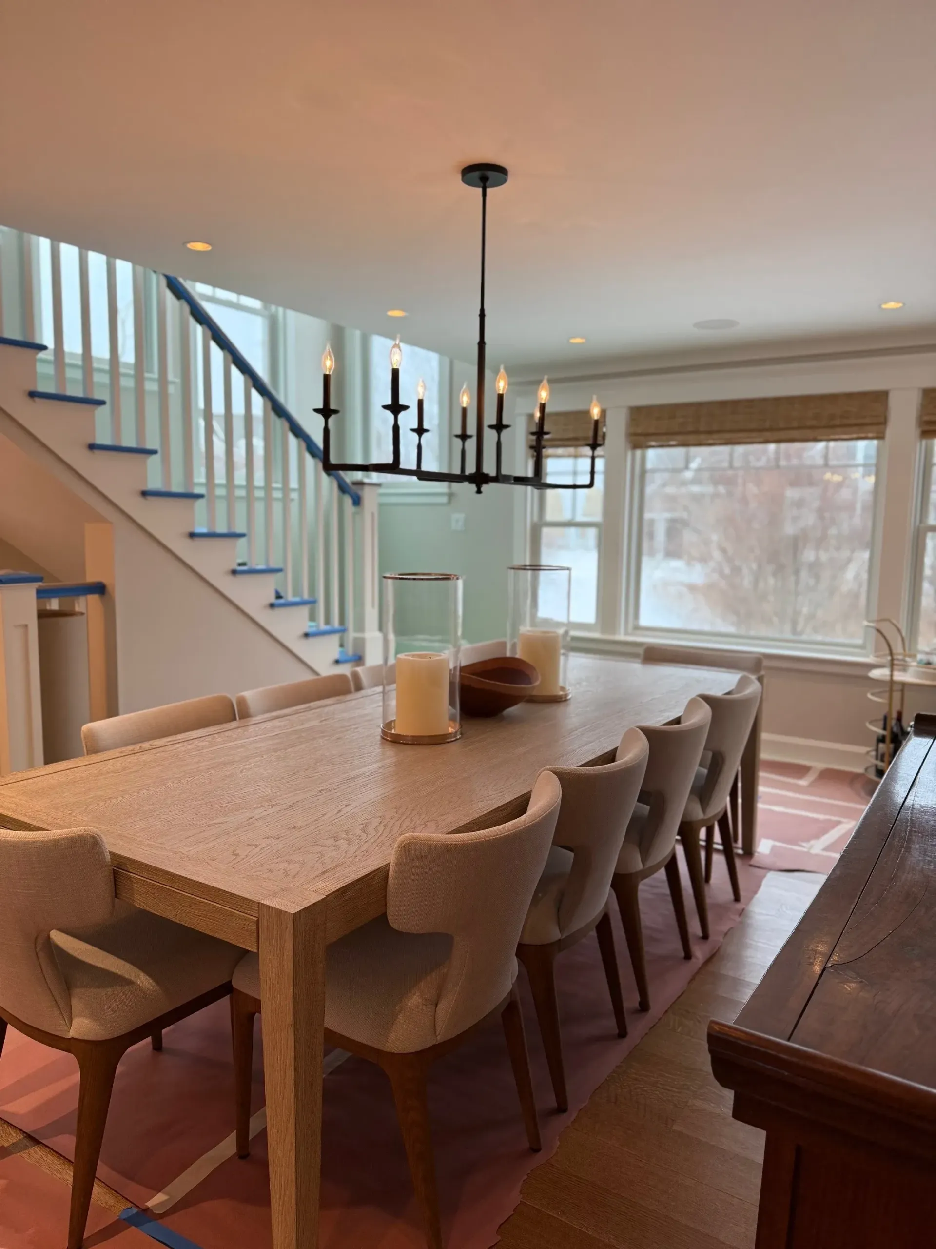 A dining room with a long table and chairs and a chandelier hanging from the ceiling.