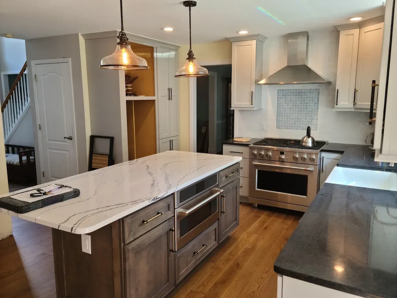 A kitchen under renovation featuring unfinished white cabinets, a yellow step ladder, and a window against plain walls.