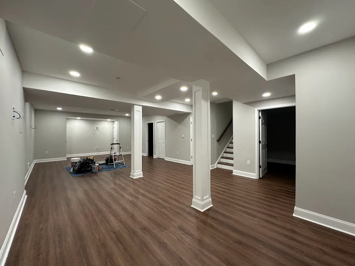 An interior view of a room under construction with unfinished drywall, exposed wooden door frames, and a window.