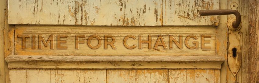 Rustic wooden sign reading “TIME FOR CHANGE” on a weathered tan wall.