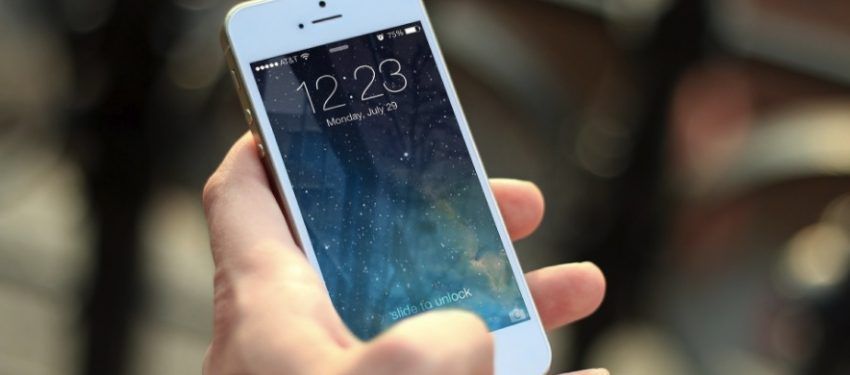 Hand holding a white smartphone with a blue lock screen displaying 2:23