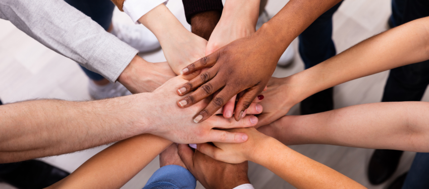 Hands stacked together in a group team gesture on a dark background