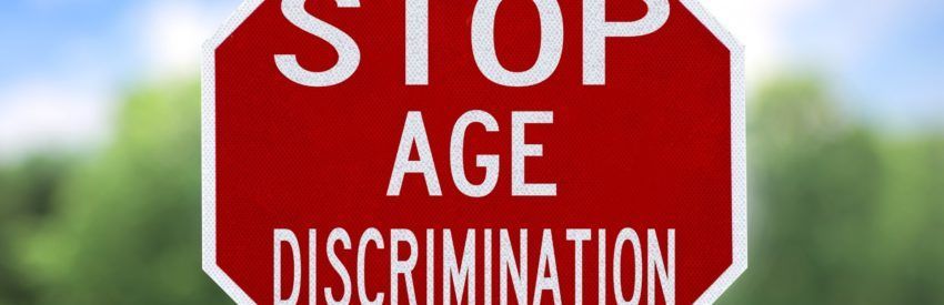 Red stop sign reading “STOP AGE DISCRIMINATION” against a blurred green background