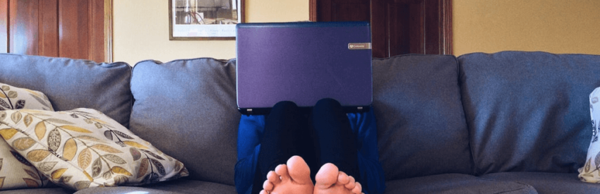 Purple folder resting on a blue couch, with feet visible in the foreground.