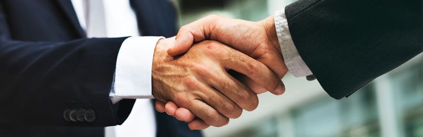 Two businesspeople in suits shaking hands in a close-up deal agreement