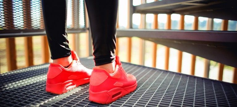 Person wearing bright red sneakers standing on a metal deck overlooking water