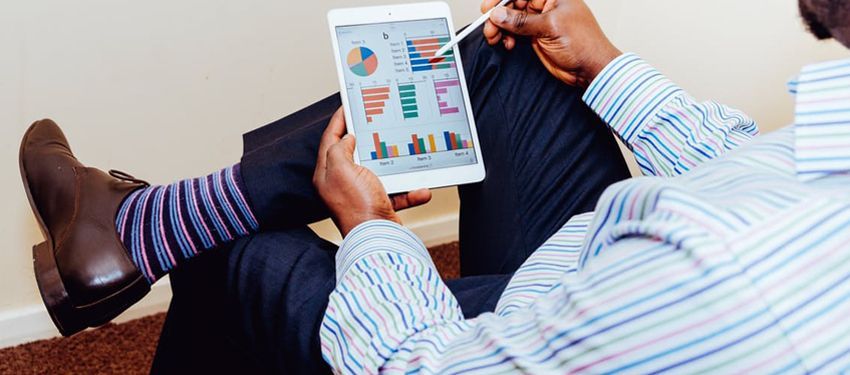 Person holding a tablet with colorful charts while reclining on a couch