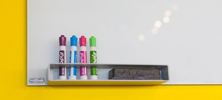 Markers and erasers on a whiteboard tray