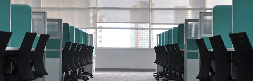 Empty modern computer lab with rows of teal chairs and desks facing large windows